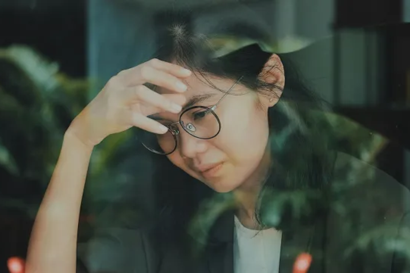 young woman with worried expression touching her forehead